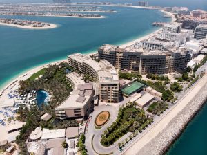 Aerial view of Palm Jumeirah, Dubai, featuring luxury beachfront resorts, turquoise waters, and iconic island views.